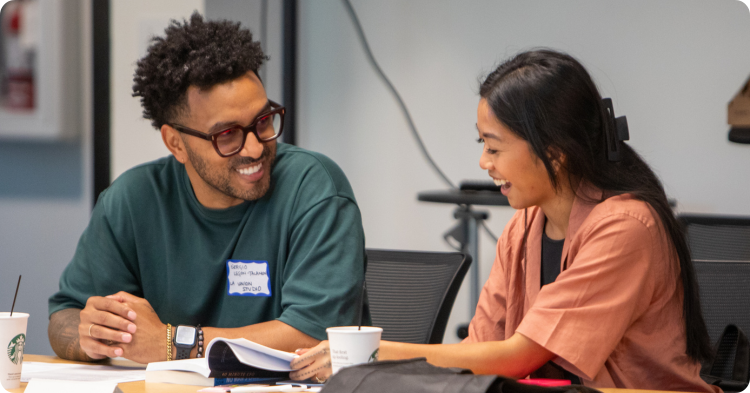 Two young entrepreneurs chatting and reviewing documents in a class. Two young entrepreneurs chatting and reviewing documents in a class.