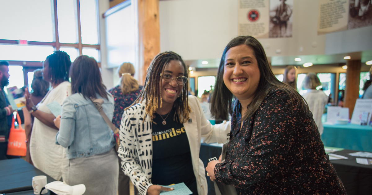 Two women stopping to pose and smile at the busy Celebrating Dreams 2024 event Two women stopping to pose and smile at the busy Celebrating Dreams 2024 event